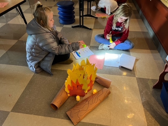 Two students reading by fake campfire