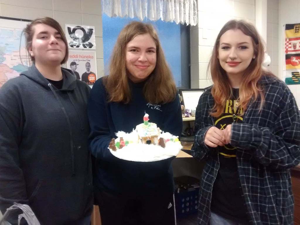 Three German Students holding a gingerbread house