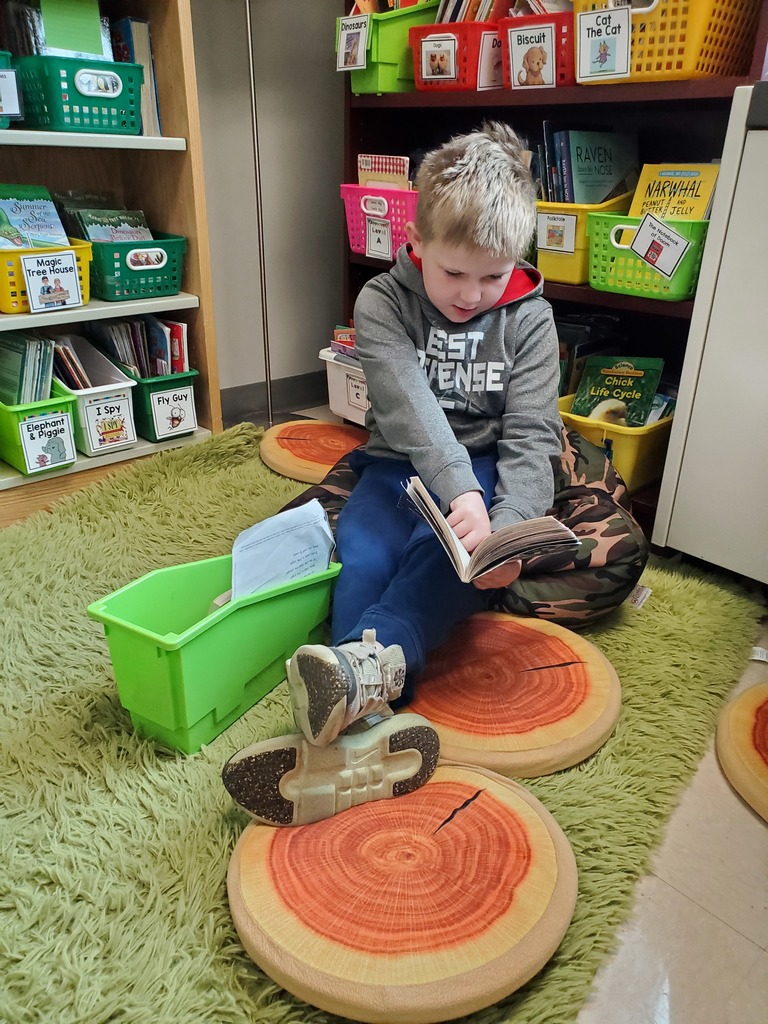 A boy reading on round pillows on the floor