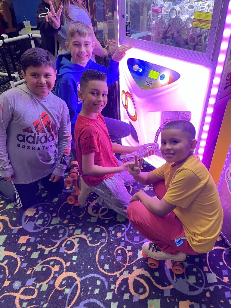 four boys playing a game at a skating rink