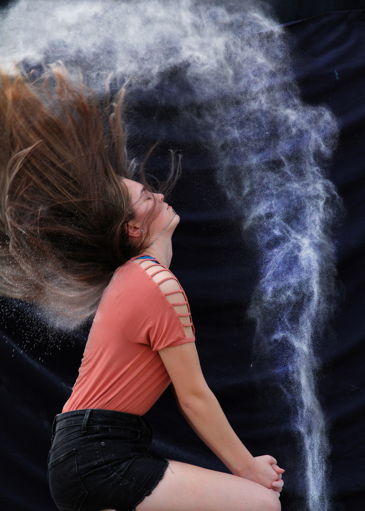 Girl with wet hair flinging it back and creating a spray of water