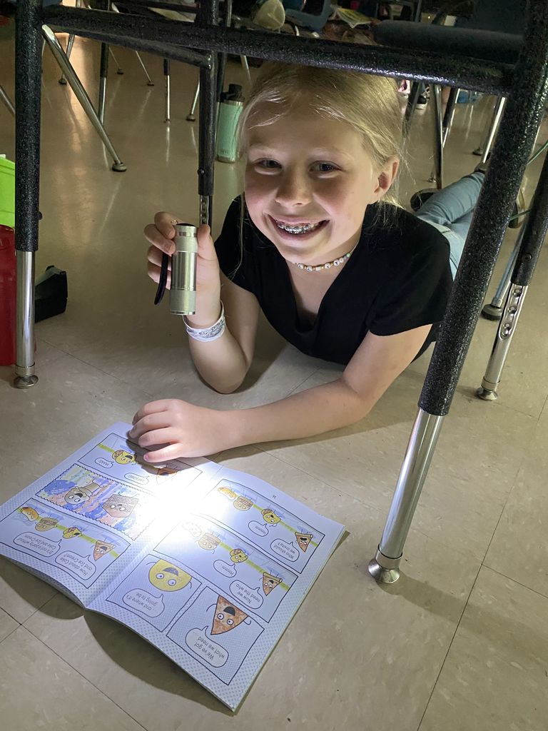 Child reading with a flashlight