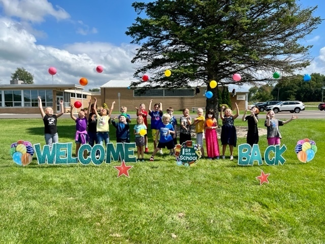 Students with balloons and a welcome back sign outside