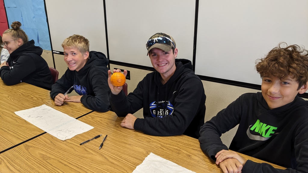 3 students with an orange