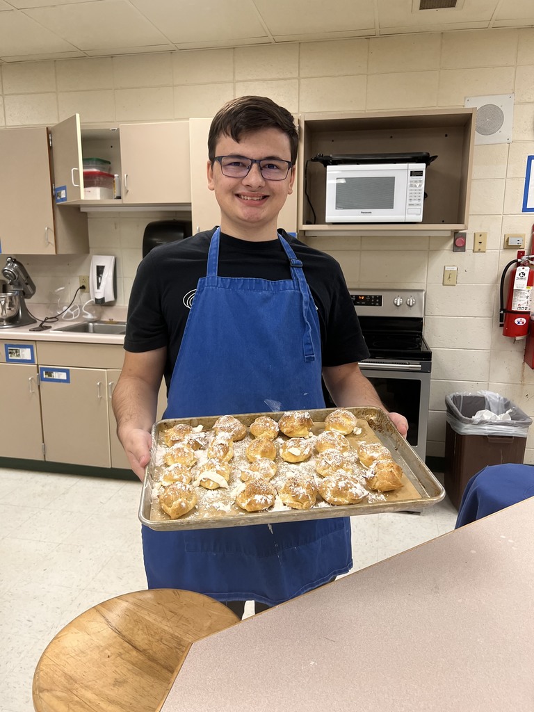 student with a pan of cream puffs
