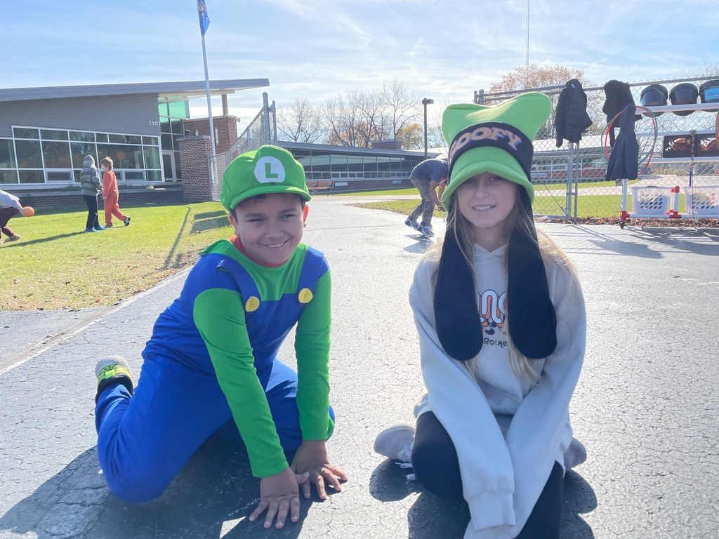 two students in costumes sitting on the playground