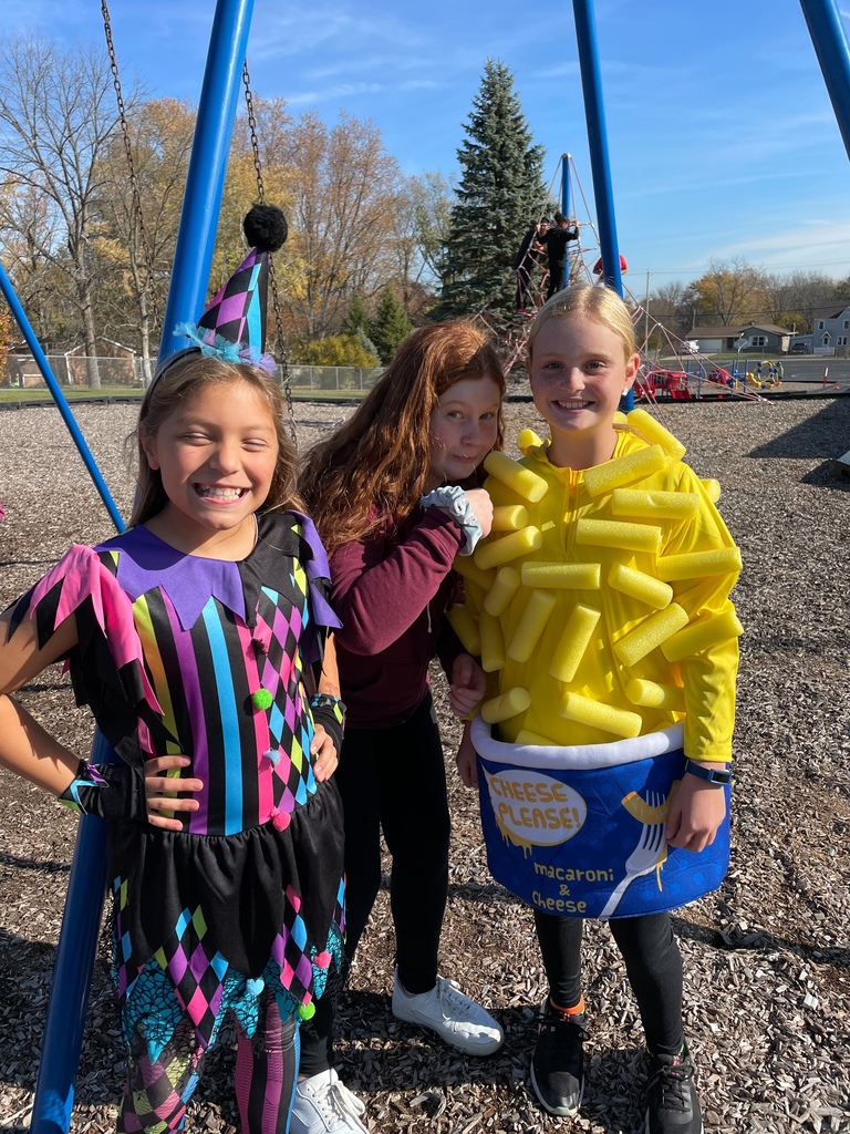 three students in costumes on the playground