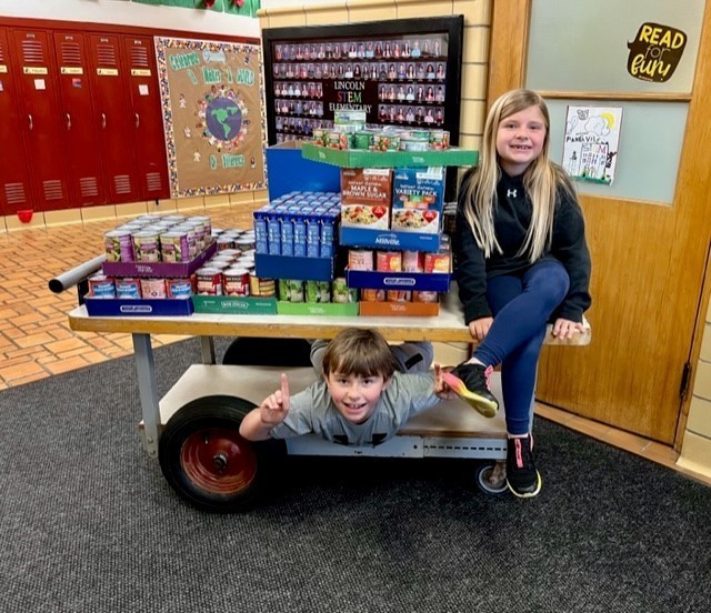 Two students on a cart with food donations